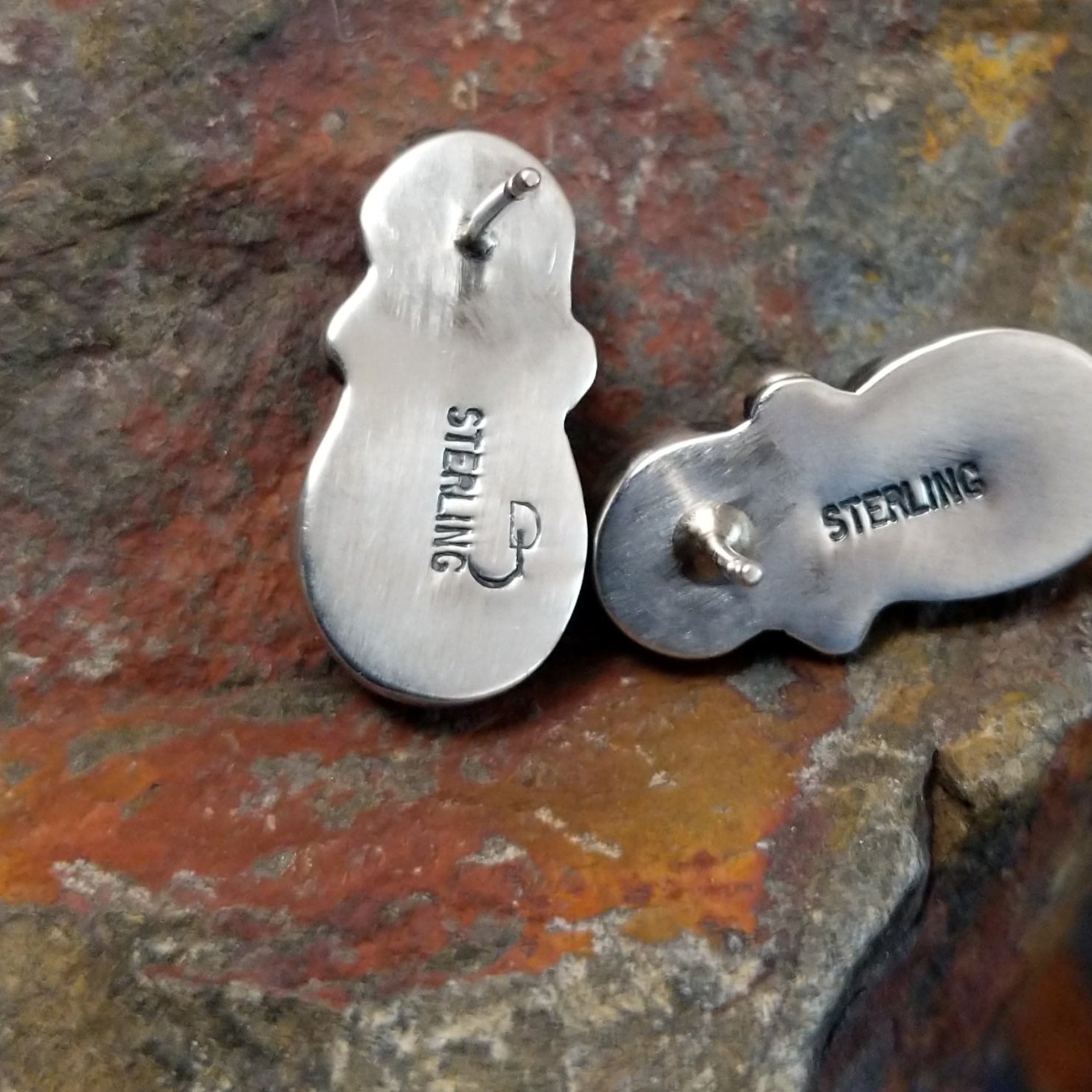 The stamped view of the navajo made golden hills turquoise earrings by J.D. features a small hallmark near the post, marking J.D.’s Navajo artistry. The turquoise stone’s edge peeks out from the simple bezel.