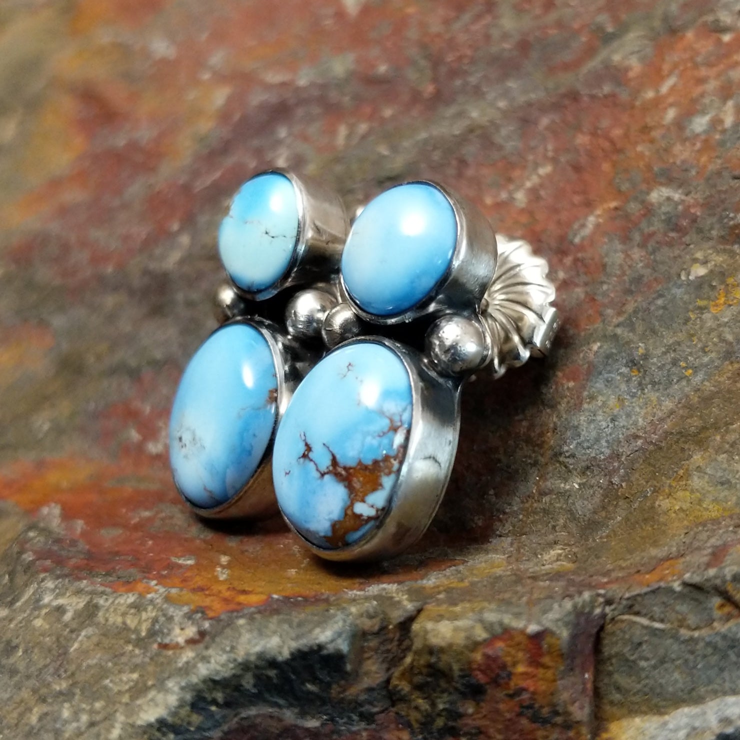 A side view of the navajo made golden hills turquoise earrings by J.D. shows the smooth edge of the turquoise stones in a simple bezel. The silver post gleams subtly against the stone’s bright blue.