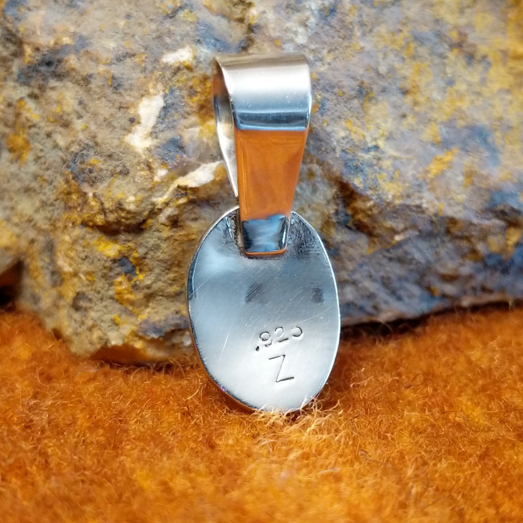 The back features the artisan's stamped initial.