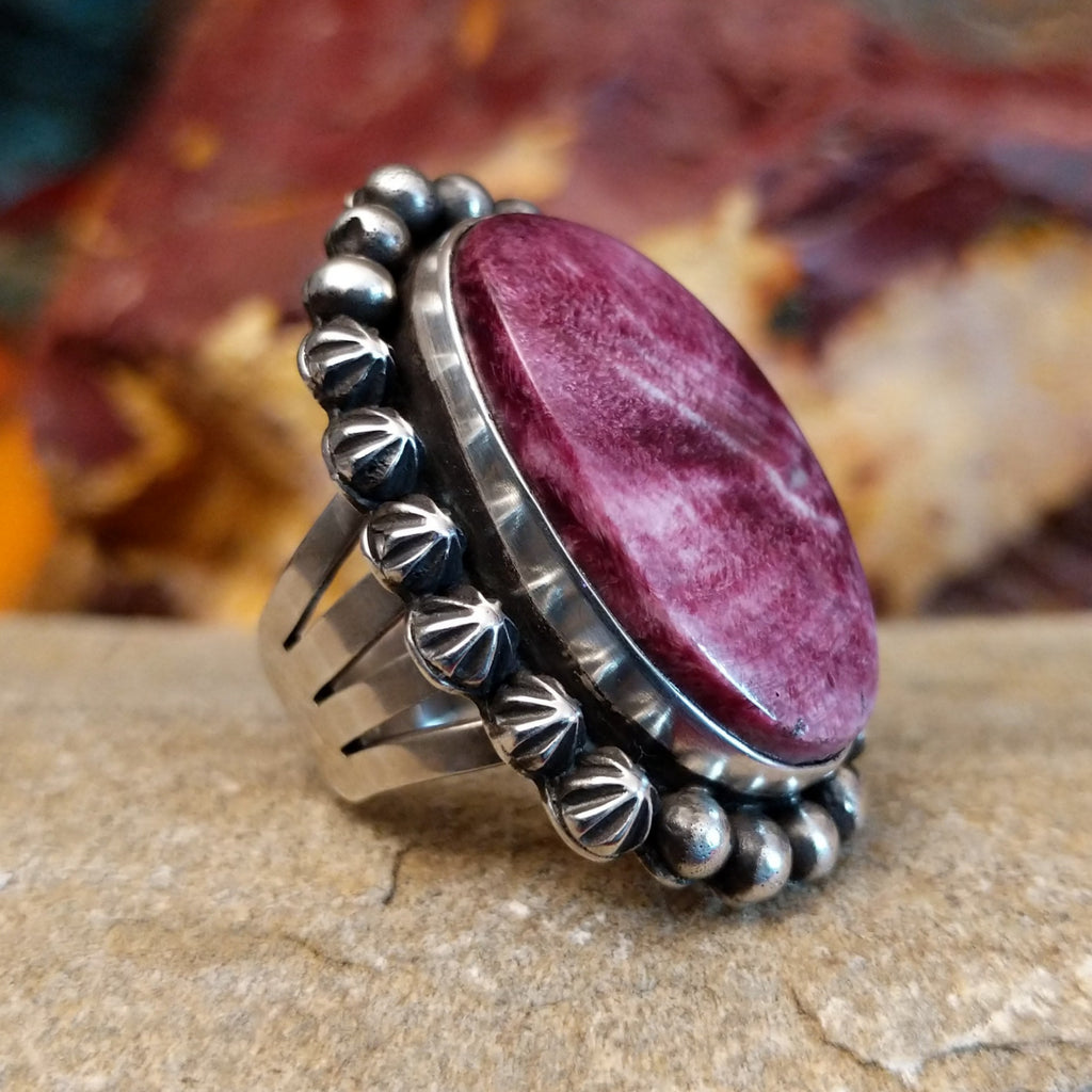 Star and dotted accents on the setting with an oval purple spiny oyster shell set inside it.