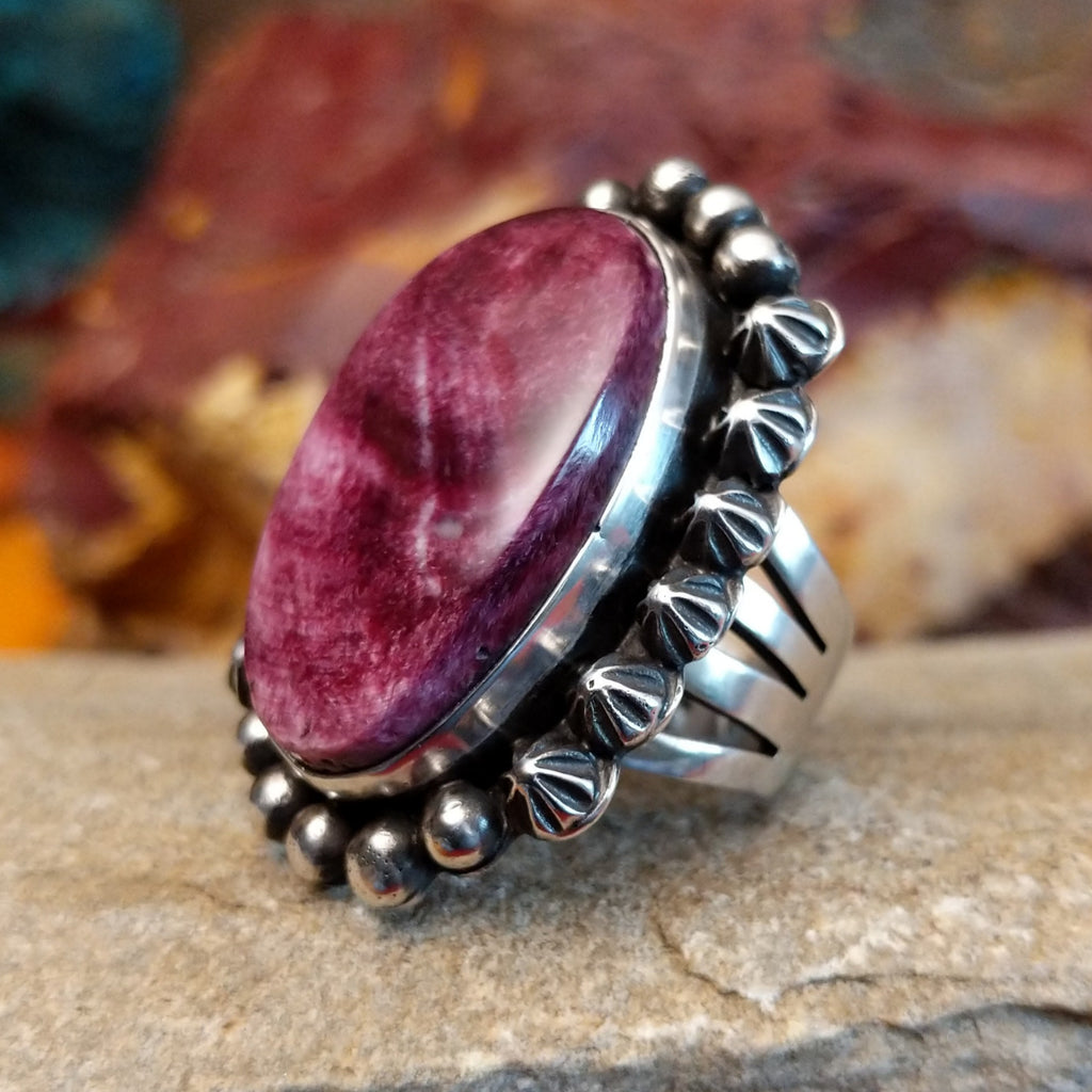 Star and dotted accents on the setting with an oval purple spiny oyster shell set inside it.