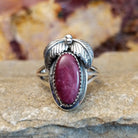 Oval purple spiny oyster shell in a notched bezel with feather motifs.