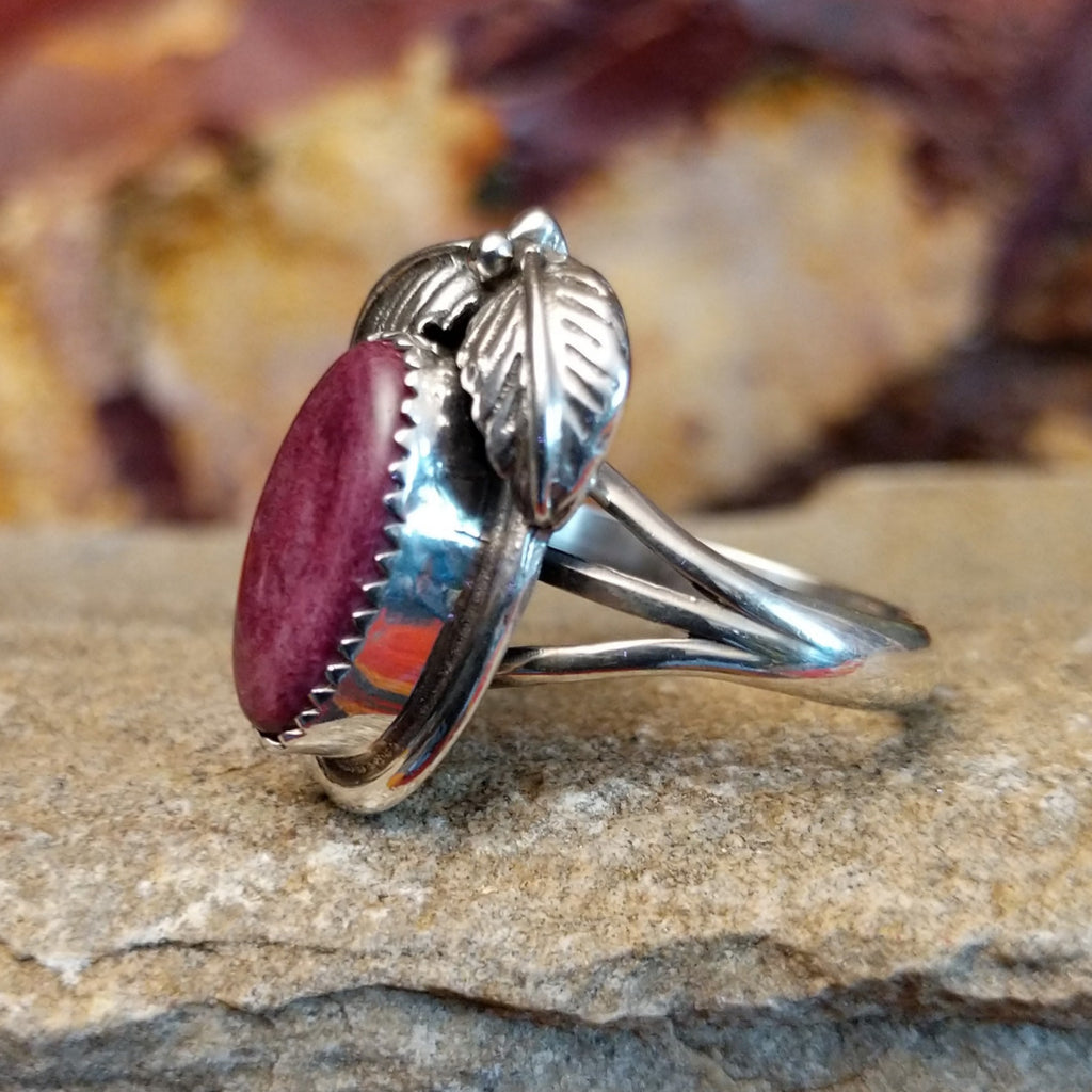 Oval purple spiny oyster shell in a notched bezel with feather motifs.