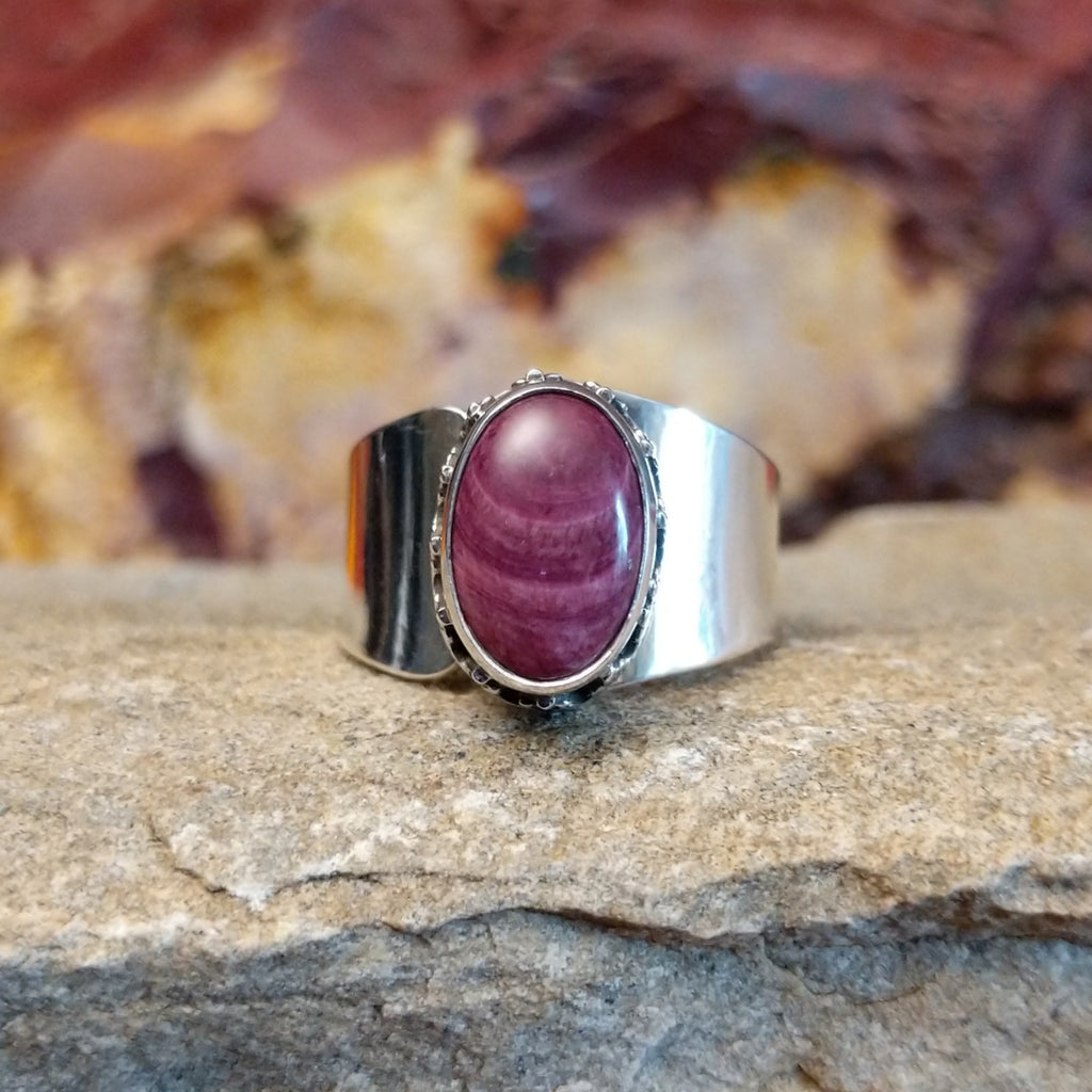Oval purple spiny oyster shell in a raised bezel with intricate accents and a smooth band.