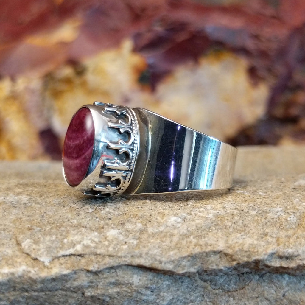 Oval purple spiny oyster shell in a raised bezel with intricate accents and a smooth band.