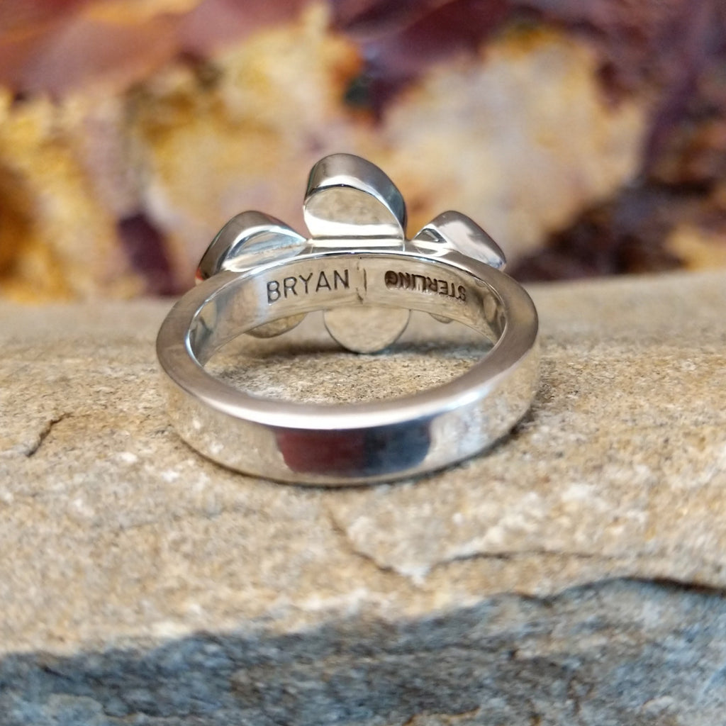 Thin polished band with stamped signature.