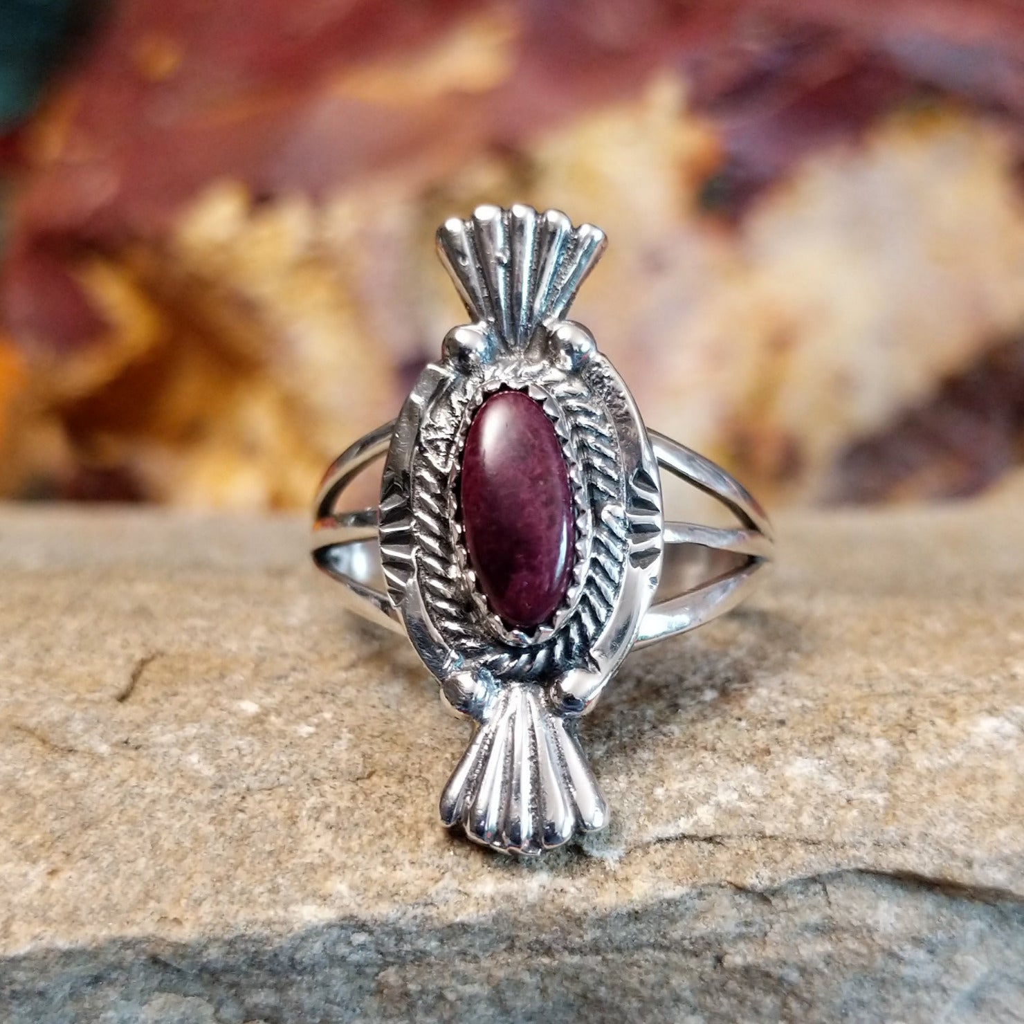 Purple spiny oyster shell set in a notched bezel with twisted rope and fan detailing on the frame.