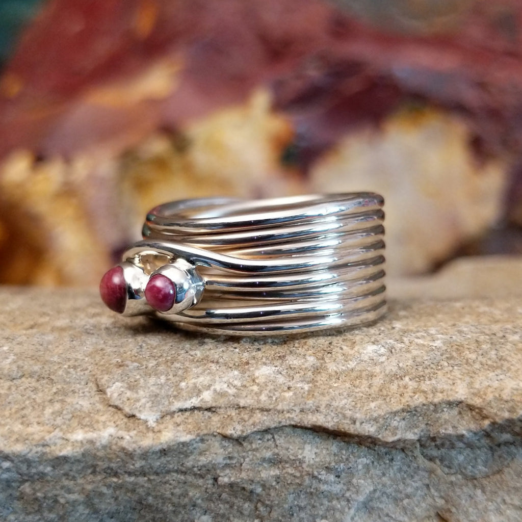 Three small purple spiny oyster shells set on a twisted, layered band.