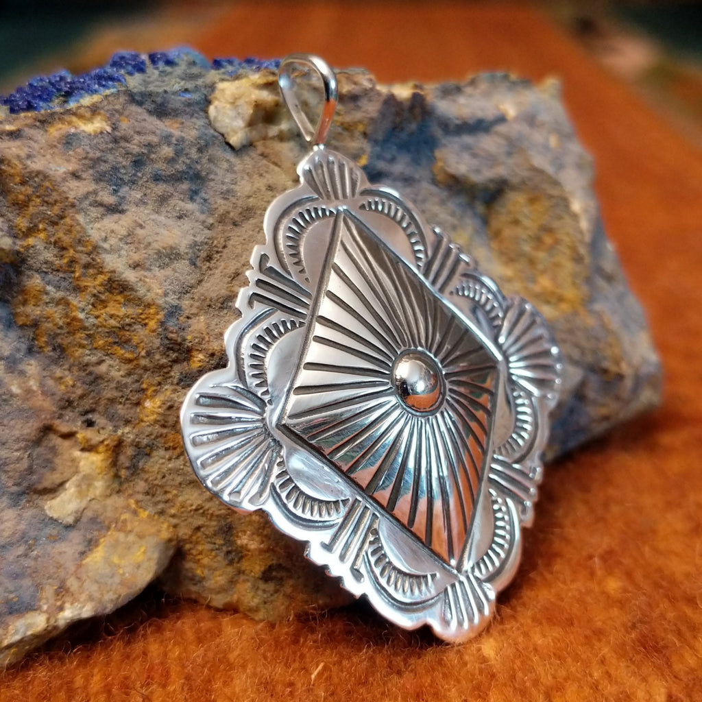 Diamond shaped sterling silver pendant with sun ray motif.