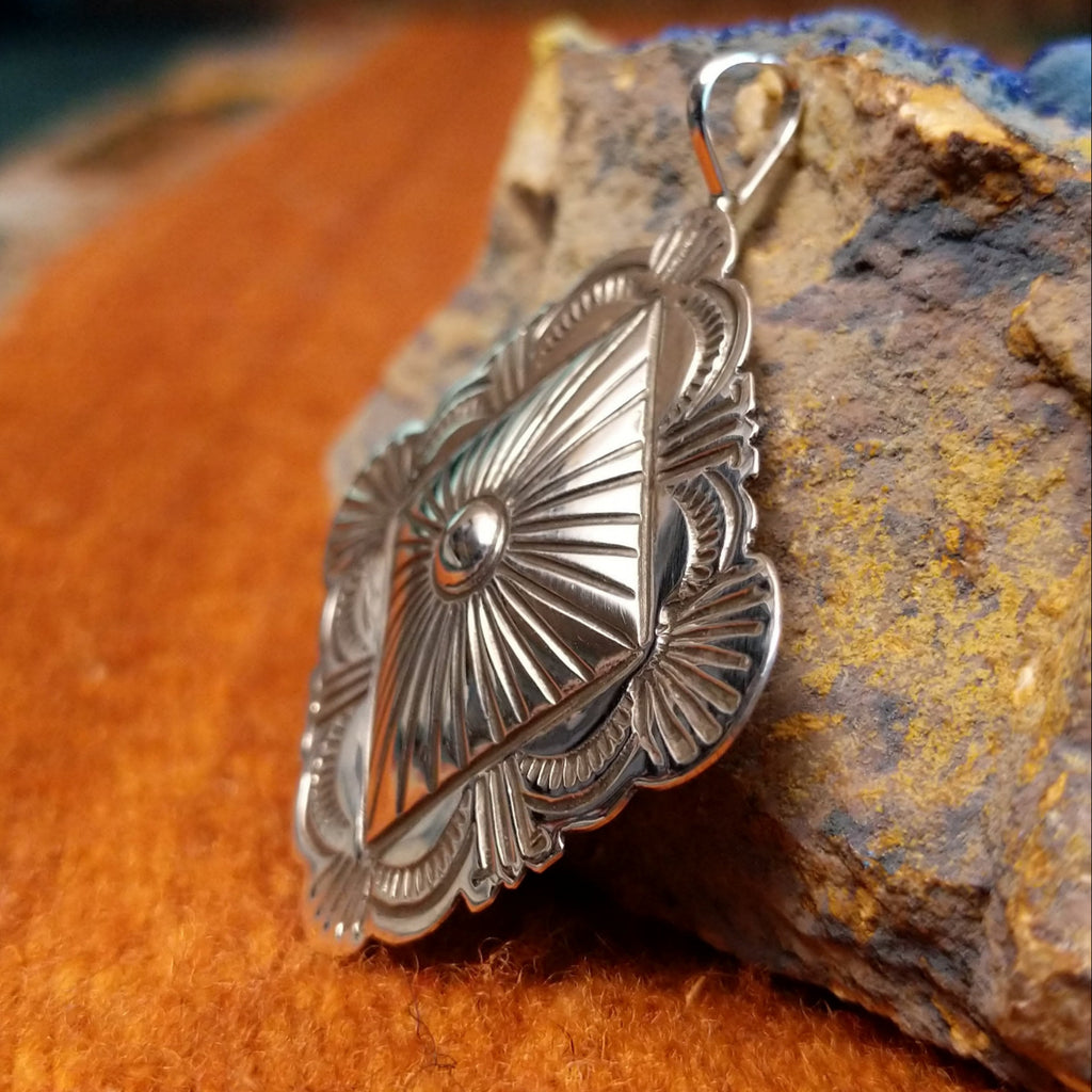 Diamond shaped sterling silver pendant with sun ray motif.