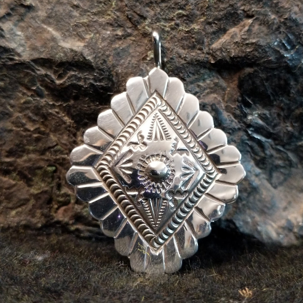 Stamped sterling silver pendant with scalloped edges and various designs.