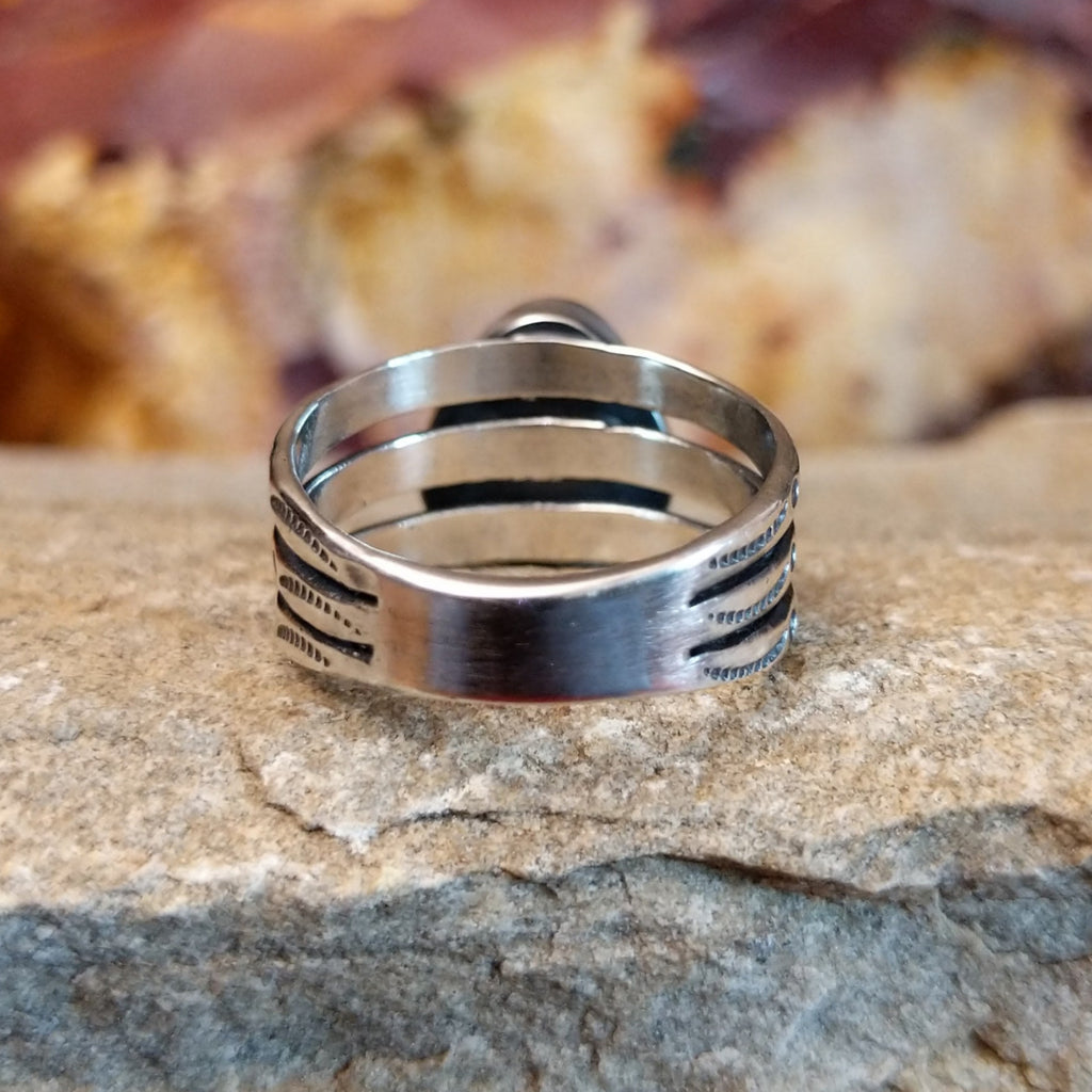 The tri-layered band features intricate stamped designs and tapered edge.