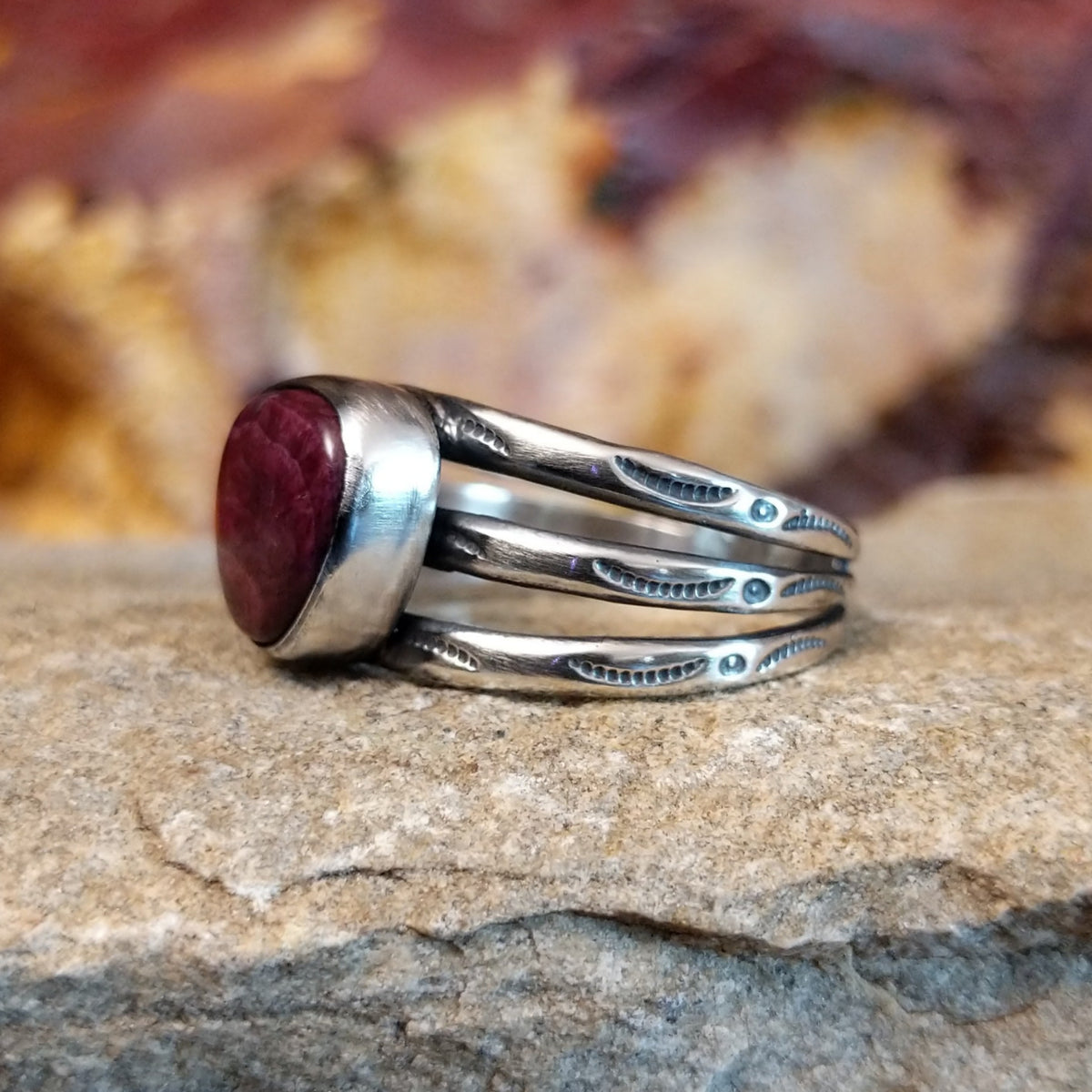 Triangular purple spiny oyster shell with a tri-band featuring ornate stamping along it.