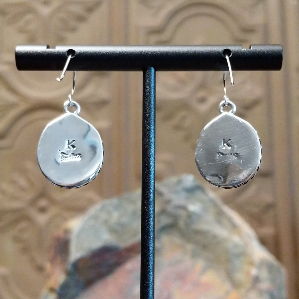 The polished sterling silver backing feature the artisan's initials and dangle hooks.