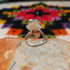 This Navajo Malachite Feather Ring by R.M. features a round green malachite stone in sterling silver surrounded by floral accents, detailed feathers, silver scrolls, and polished beadwork; underside view.