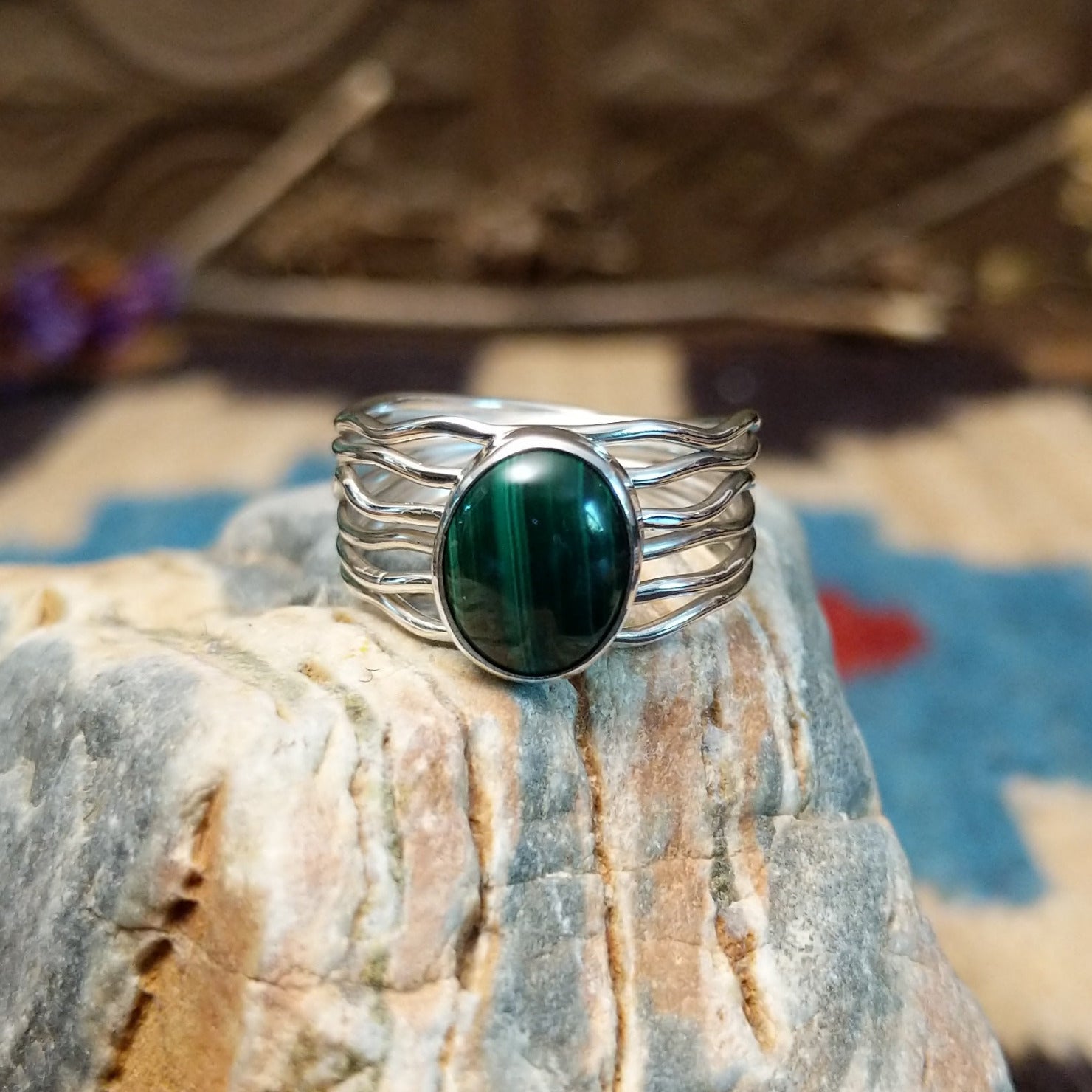 Sterling silver ring with malachite set in the raised, round bezel and silver strands making up the band.