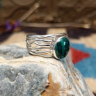 Sterling silver ring with malachite set in the raised, round bezel and silver strands making up the band.