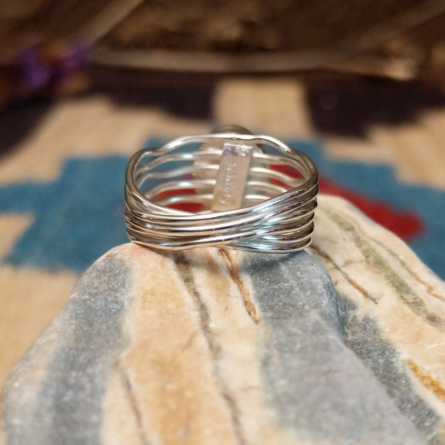 Sterling silver ring with malachite set in the raised, round bezel and silver strands making up the band.