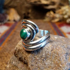 Sterling silver ring with malachite set in the bezel and framed by swirling silverwork.