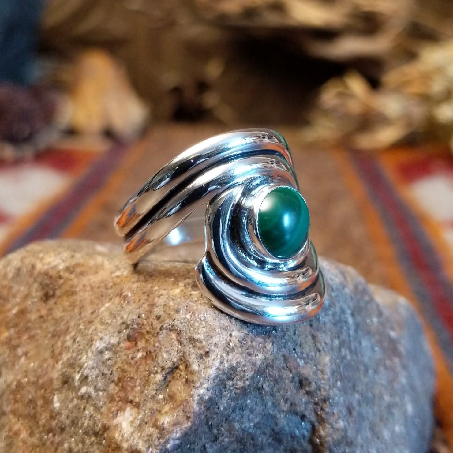 Sterling silver ring with malachite set in the bezel and framed by swirling silverwork.
