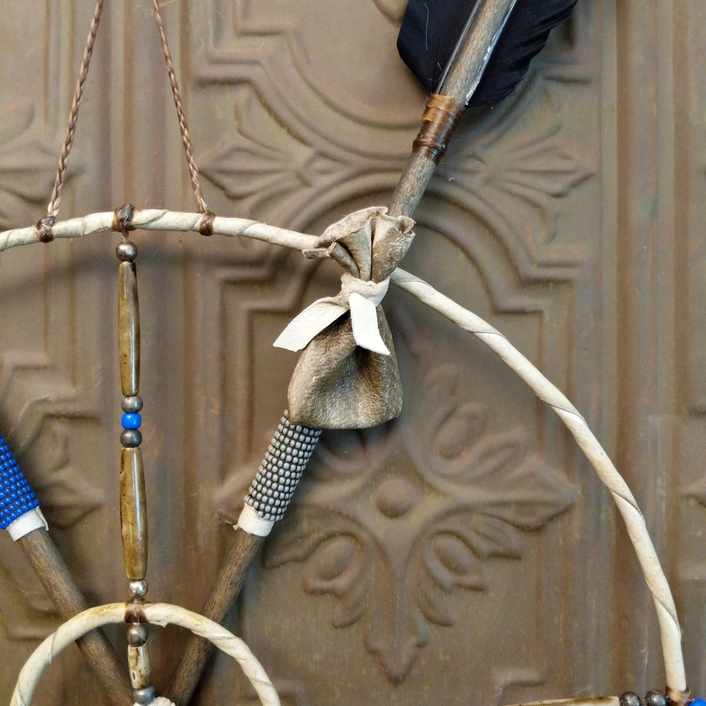 Mandela made from wood, with arrows, beads, feather, and buffalo bone set with different meanings.