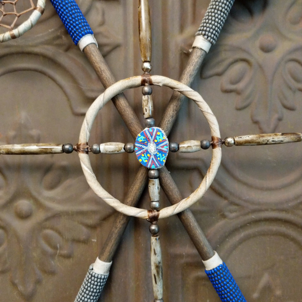 Mandela made from wood, with arrows, beads, feather, and buffalo bone set with different meanings.