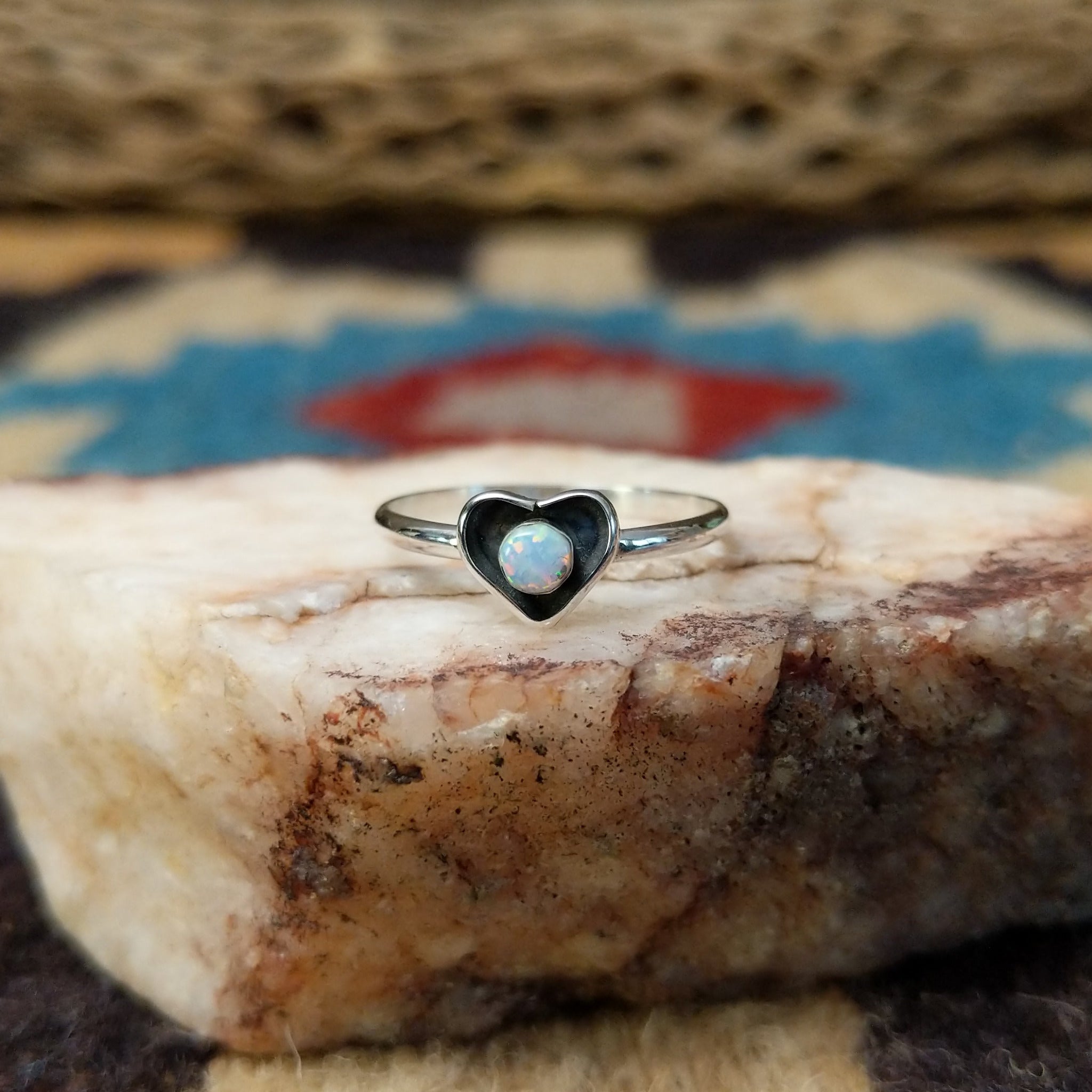 Navajo manmade opal heart ring, featuring a heart-shaped shimmering opal with vibrant flashes of color set in a handcrafted sterling silver band.