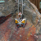 Navajo multistone butterfly pendant by K.S. featuring golden-yellow, reddish-brown, black, and white stone inlay set in polished silver butterfly wings.