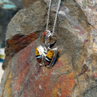 Navajo multistone butterfly pendant by K.S. featuring golden-yellow, reddish-brown, black, and white stone inlay set in polished silver butterfly wings; side view.