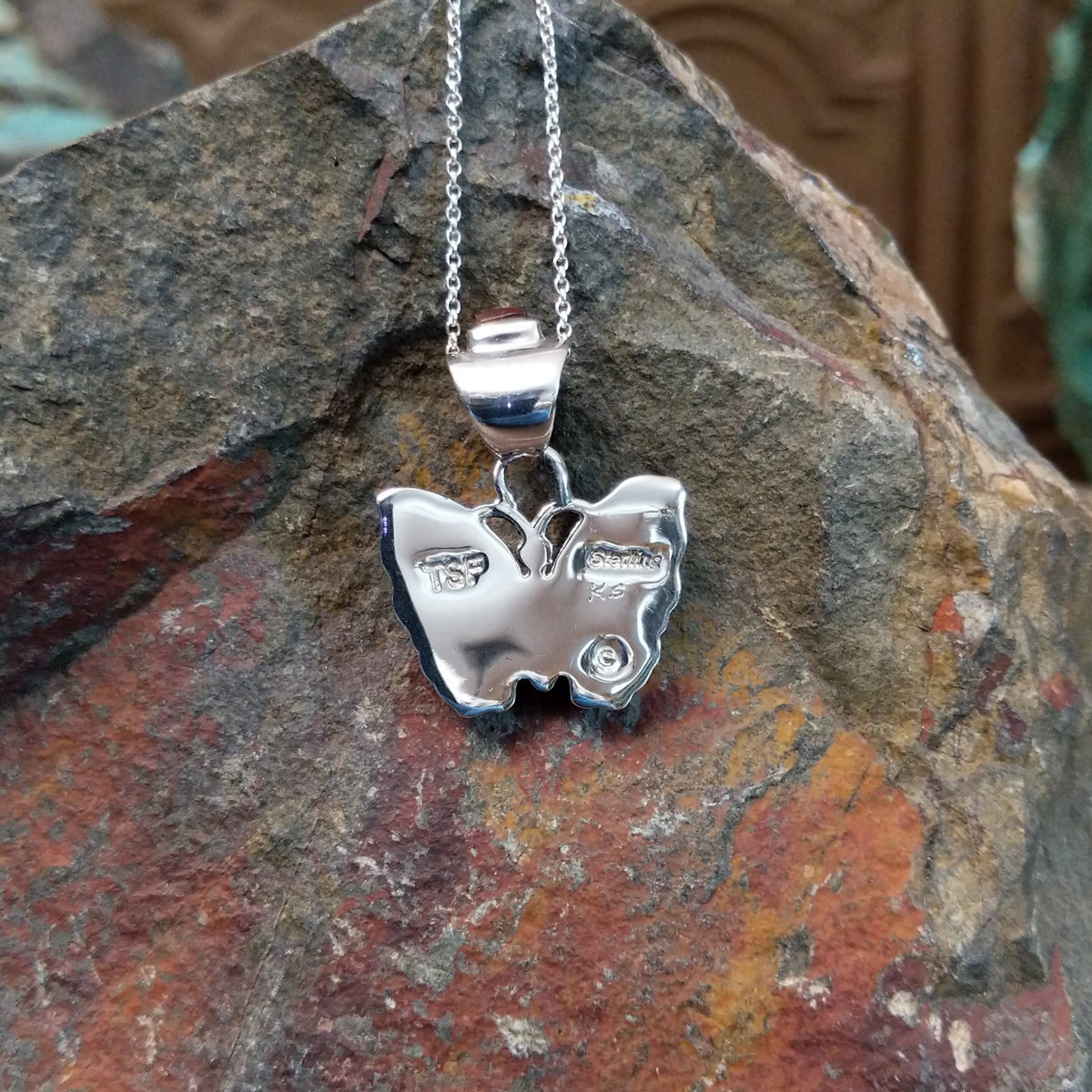 Navajo multistone butterfly pendant by K.S. featuring golden-yellow, reddish-brown, black, and white stone inlay set in polished silver butterfly wings; artisan and Sterling Silver stamp.