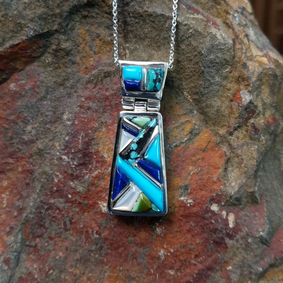 Navajo multistone cobblestone inlay pendant by J.Y. featuring turquoise, lapis, black matrix turquoise, white, and green stone inlay in a geometric sterling silver design.