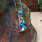 Navajo multistone cobblestone inlay pendant by J.Y. featuring turquoise, lapis, black matrix turquoise, white, and green stone inlay in a geometric sterling silver design; side view.