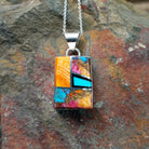 Handcrafted sterling silver compressed stone inlay pendant by S.L., featuring a colorful geometric Navajo design.