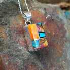 Handcrafted sterling silver compressed stone inlay pendant by S.L., featuring a colorful geometric Navajo design; side view.