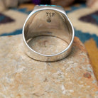 Sterling silver Navajo multistone inlay ring featuring turquoise, orange spiny oyster shell, lapis, and geometric mosaic inlay on a polished signet-style band; underside view.