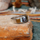 Navajo sterling silver ring by J.C. featuring geometric multistone inlay with black onyx, tiger’s eye, and assorted natural stones separated by silver dividers; side view.