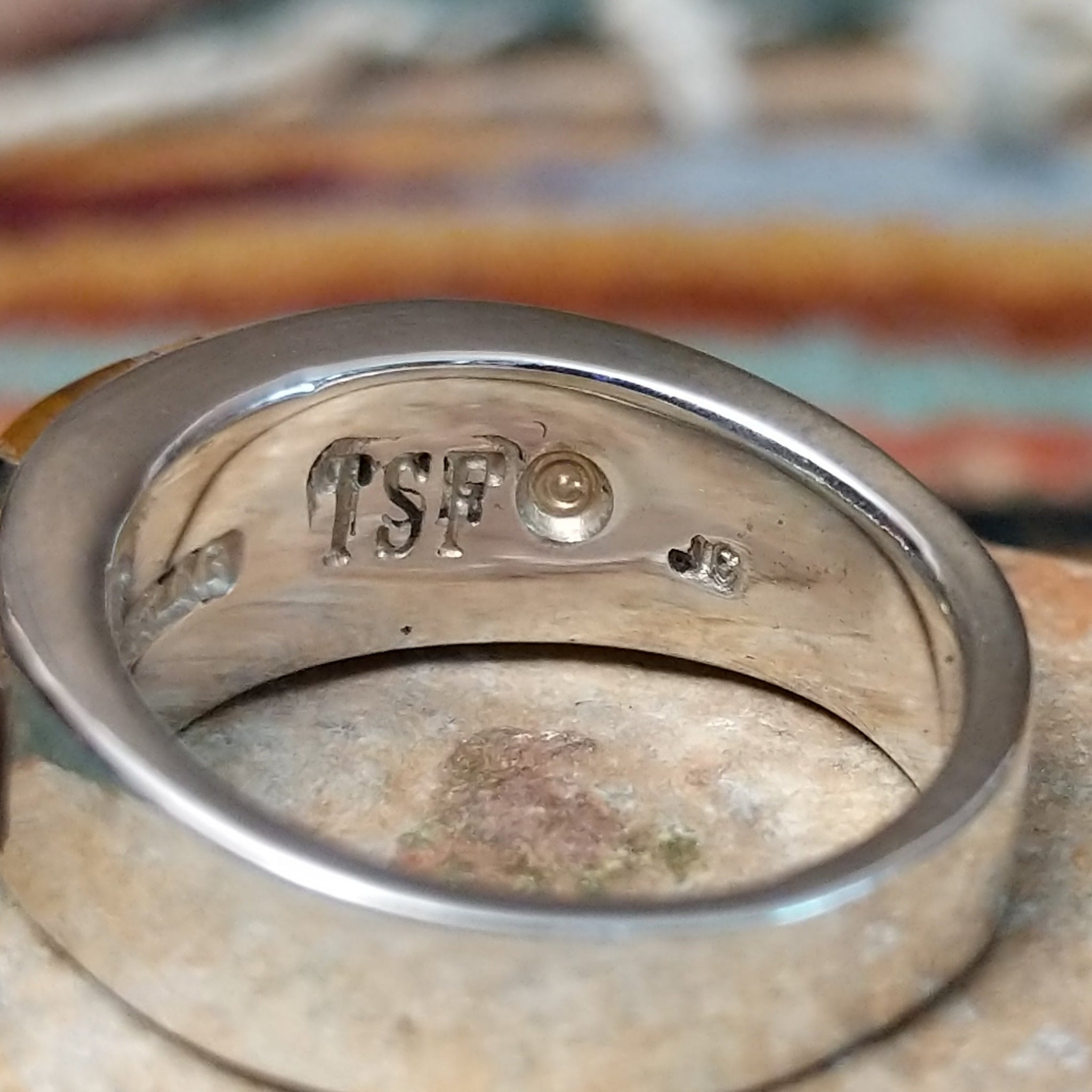 Navajo sterling silver ring by J.C. featuring geometric multistone inlay with black onyx, tiger’s eye, and assorted natural stones separated by silver dividers; artisan and Sterling Silver stamp.