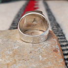 Navajo multistone inlay ring by O.J. featuring a rectangular geometric design with orange shell, turquoise, blue, green, and black inlay set in a polished silver band; underside view.