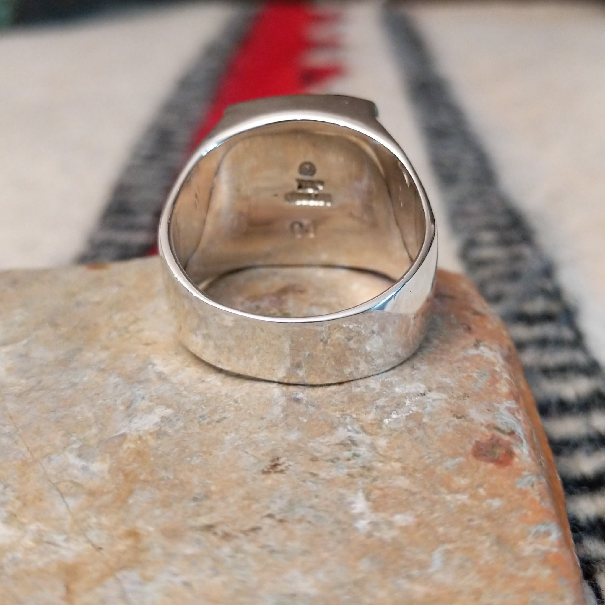 Navajo multistone inlay ring by O.J. featuring a rectangular geometric design with orange shell, turquoise, blue, green, and black inlay set in a polished silver band; underside view.