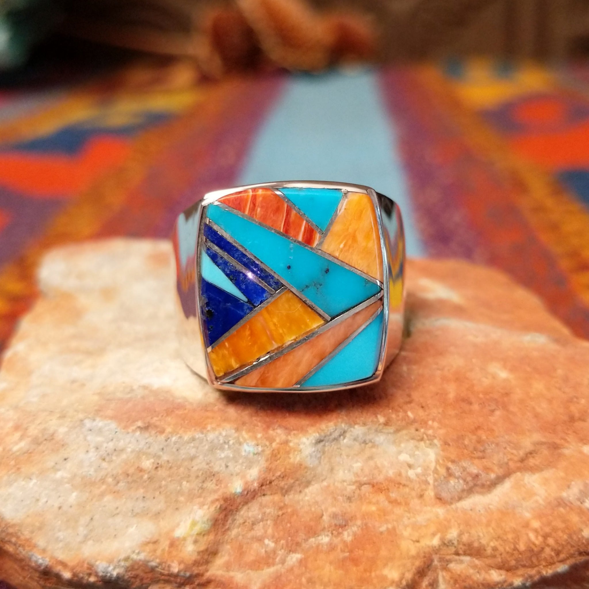 Navajo Multistone Inlay Ring by R.L. featuring geometric turquoise, lapis, and orange and red-toned spiney oyster shell inlay separated by Sterling Silver channels on a polished silver band.