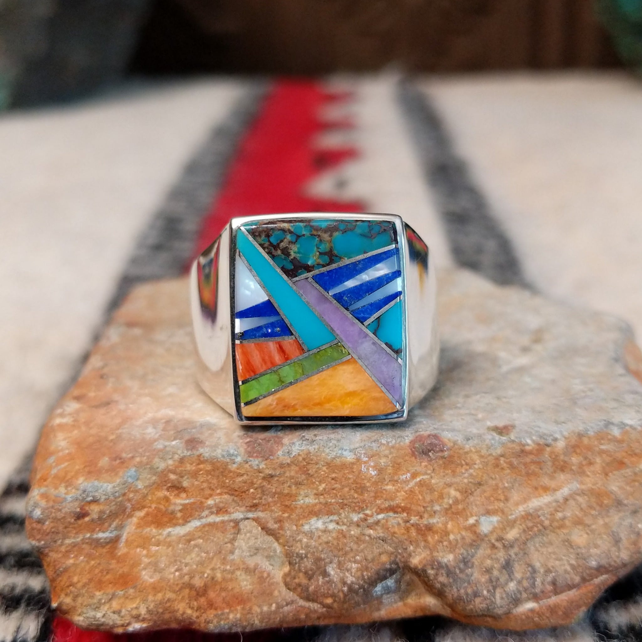 Navajo multistone inlay ring by V.Y. featuring a rectangular geometric design with turquoise, blue, purple, green, orange, and white inlay set in a wide polished silver band.