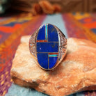 Navajo Oval Lapis Inlay Ring by T.L. featuring geometric blue lapis inlay with turquoise and red accents, Sterling Silver channels, and detailed stamped silverwork.
