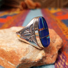 Navajo Oval Lapis Inlay Ring by T.L. featuring geometric blue lapis inlay with turquoise and red accents, Sterling Silver channels, and detailed stamped silverwork; side view.