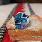 Navajo oval multistone inlay ring by E.D. featuring turquoise, blue, green, and purple stones arranged in a geometric mosaic with silver channel accents and a polished silver band.