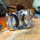 Wide Navajo silver cuff with polished overlapping bands and large open sections.