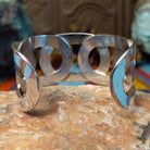 Wide Navajo silver cuff with polished overlapping bands and large open sections.