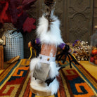 This distinctive Navajo Protection Dancer Kachina by Debbie James features a hand-painted wooden figure with a white feather headdress, natural feathers, leather ties, fur accents, colorful fabric details, and a wooden display base; back view.