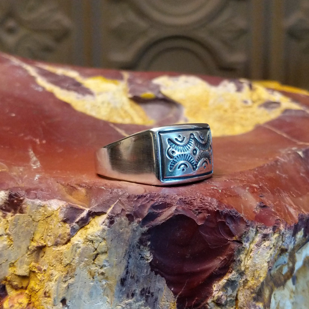 Sterling silver ring with a raised bezel featuring intricate designs.