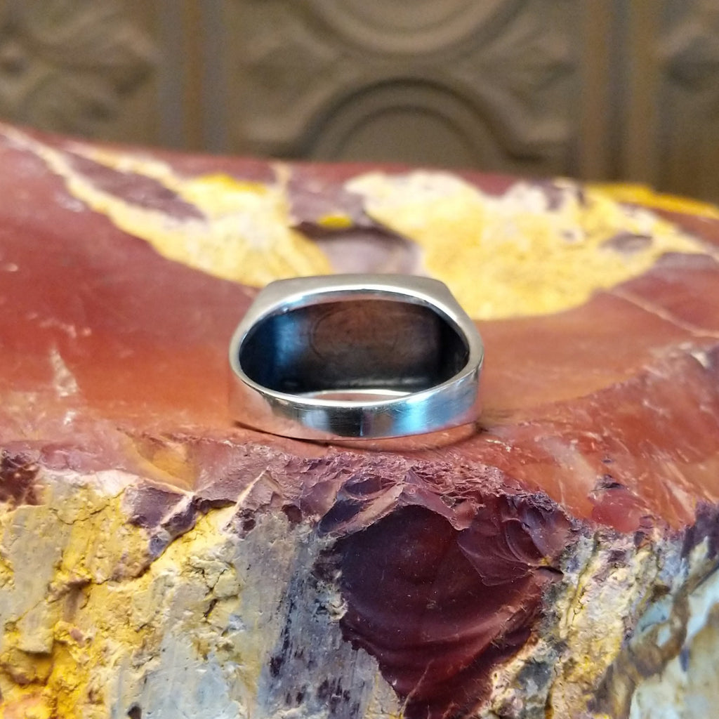 Sterling silver ring with a raised bezel featuring intricate designs.