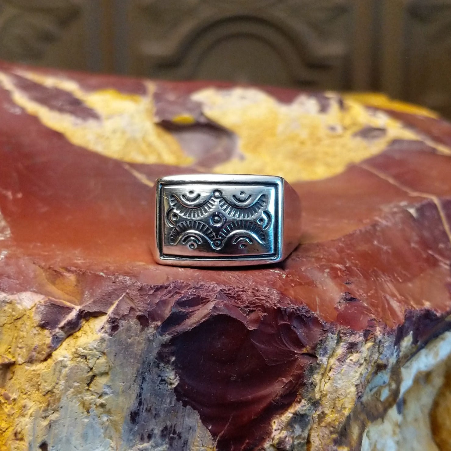 Sterling silver ring with a raised bezel featuring intricate designs.